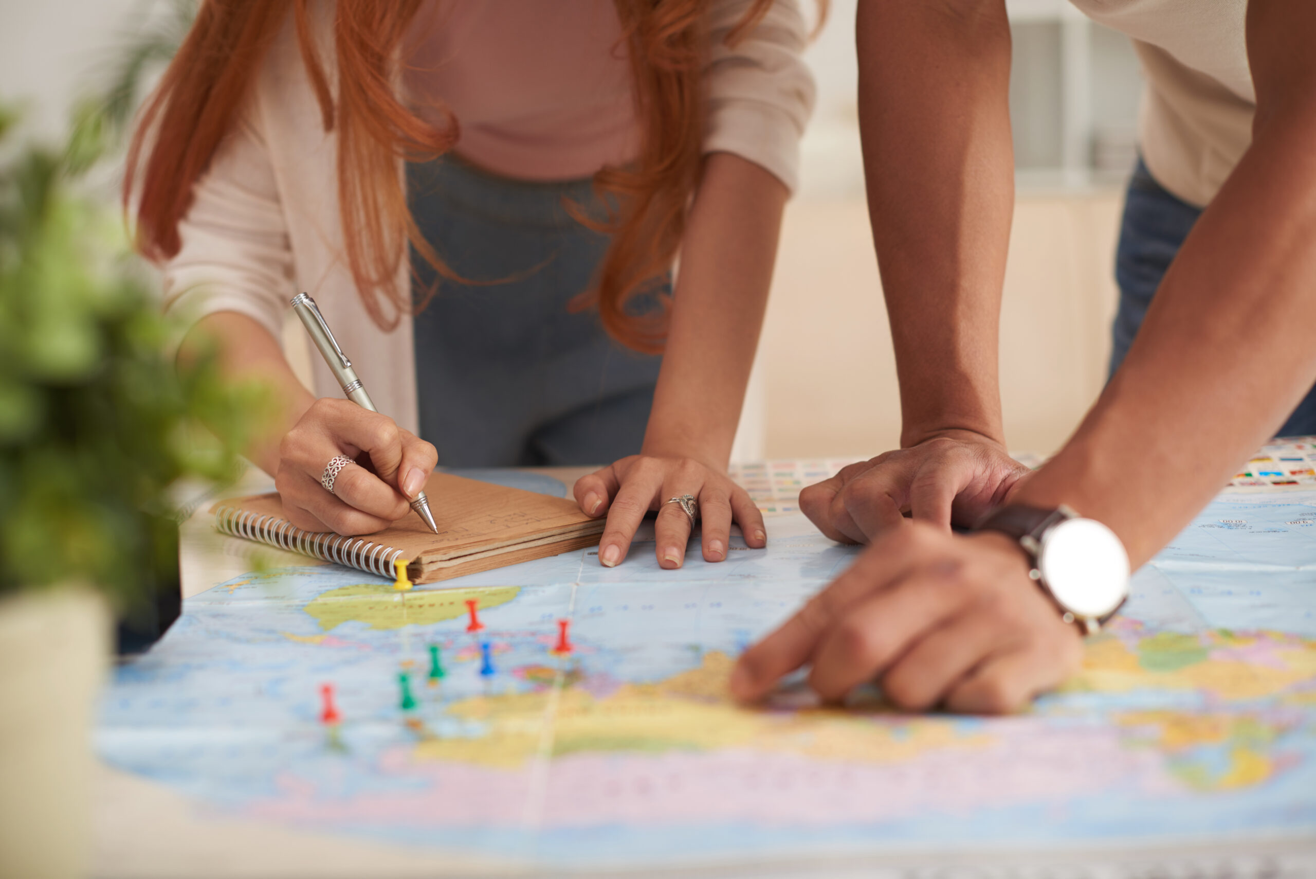 Closeup shot of young couple  marking travelling destinations on map and planning vacation budget